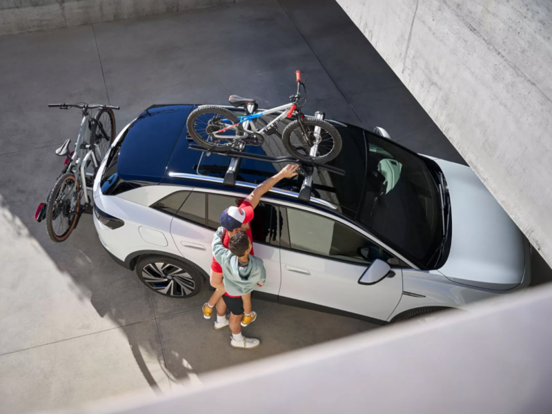 Un padre con su hijo montando unas bicicletas en lo alto de un Volkswgen