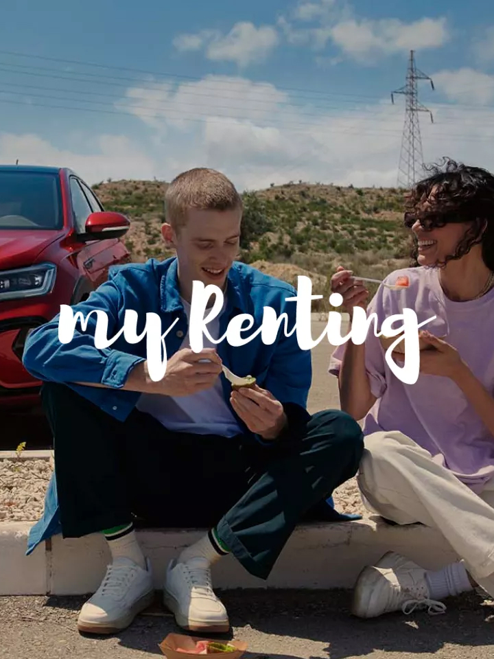 Dos chicos sentados delante de un Volkswagen con el logo my renting