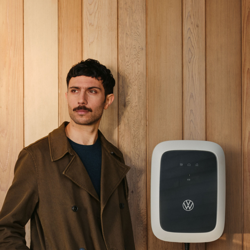 Un chico junto a un Wallbox en una pared de madera