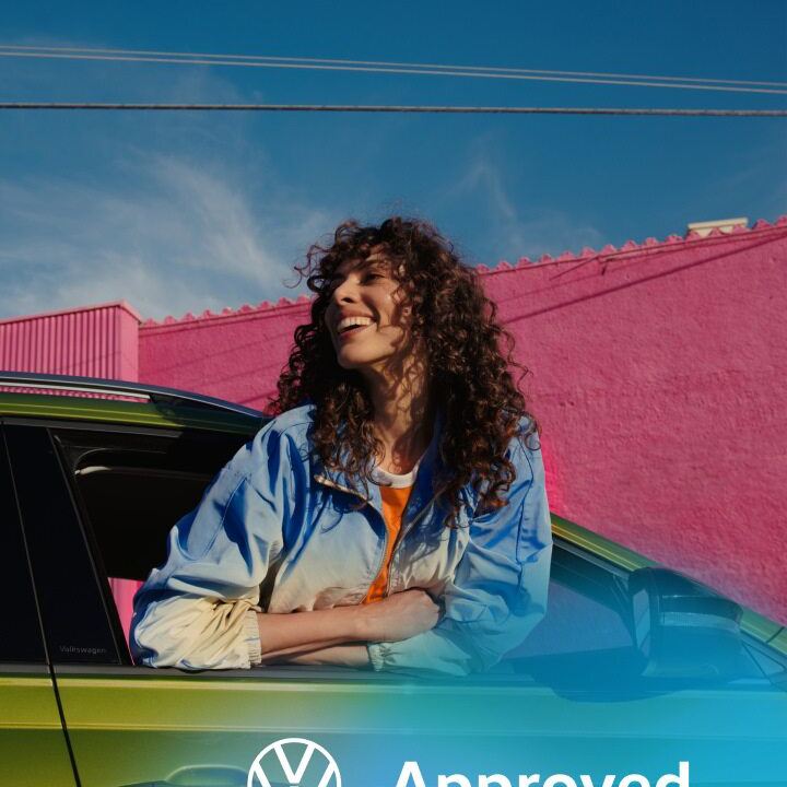 Una chica sonriendo asomada por la ventana de un Volkswagen de ocasión