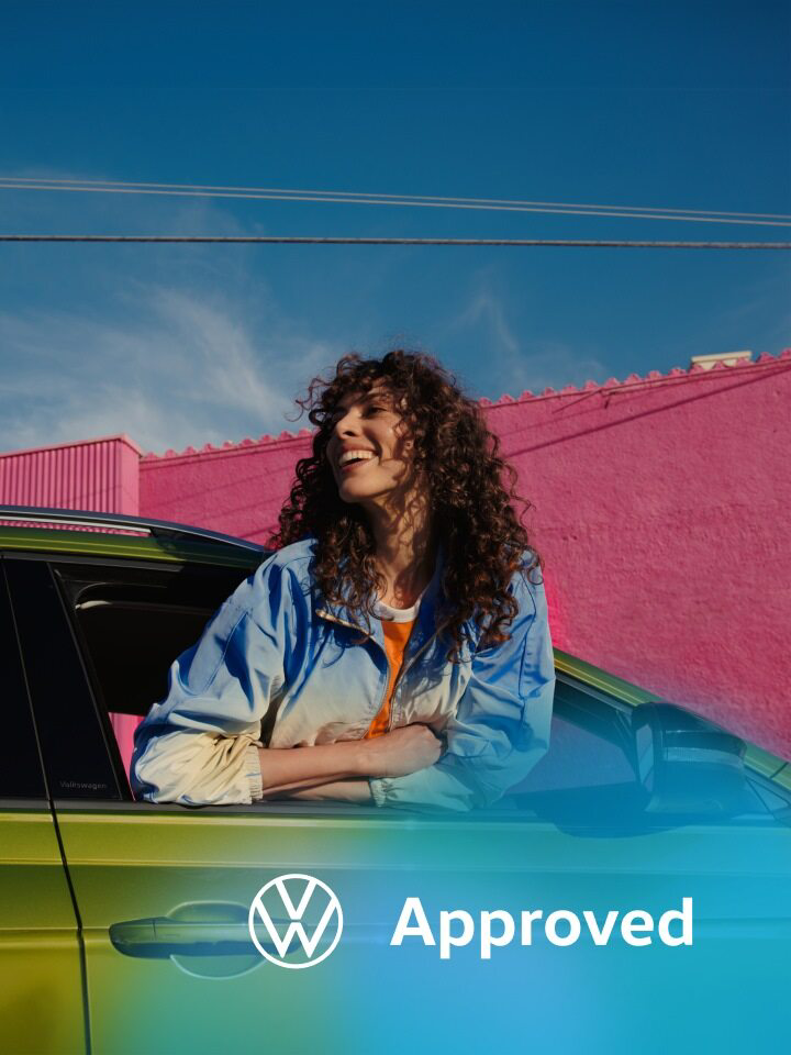 Una chica sonriendo asomada por la ventana de un Volkswagen de ocasión