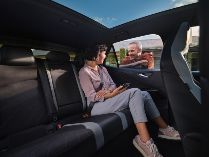 Plano interior de un vehículo Volkswagen financiado a medida con una persona sentada dentro y otra que se asoma por la ventanilla