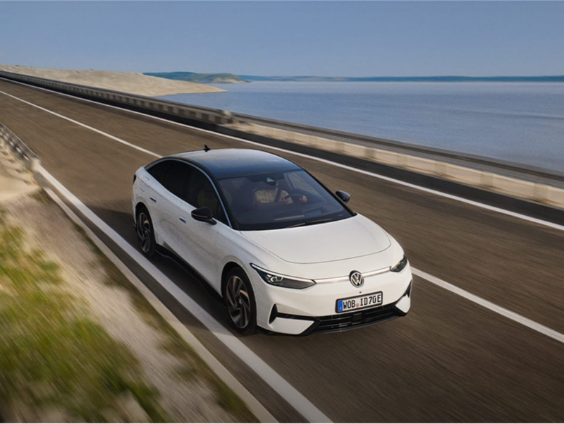 Volkswagen ID.7 blanco visto de frente en una carretera frente al mar