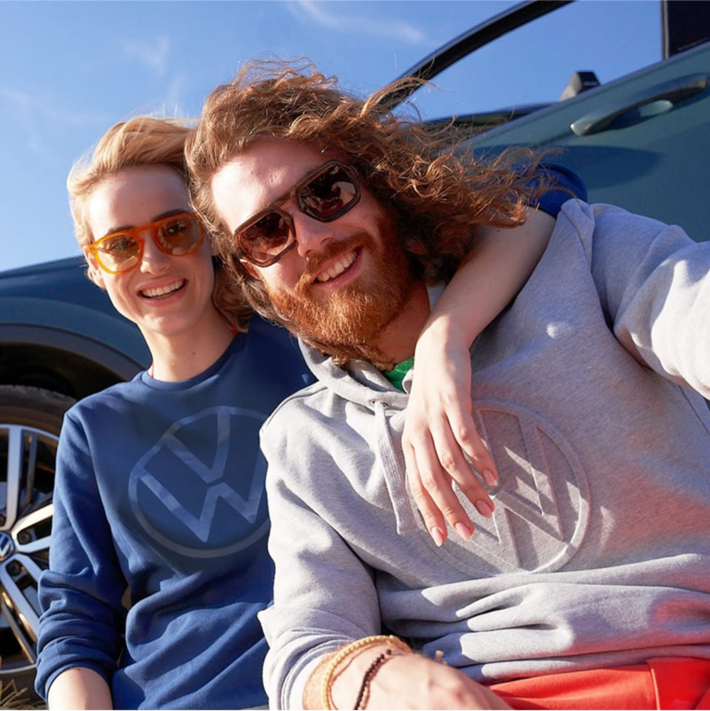 Una pareja sonriendo con sudaderas de Volkswagen