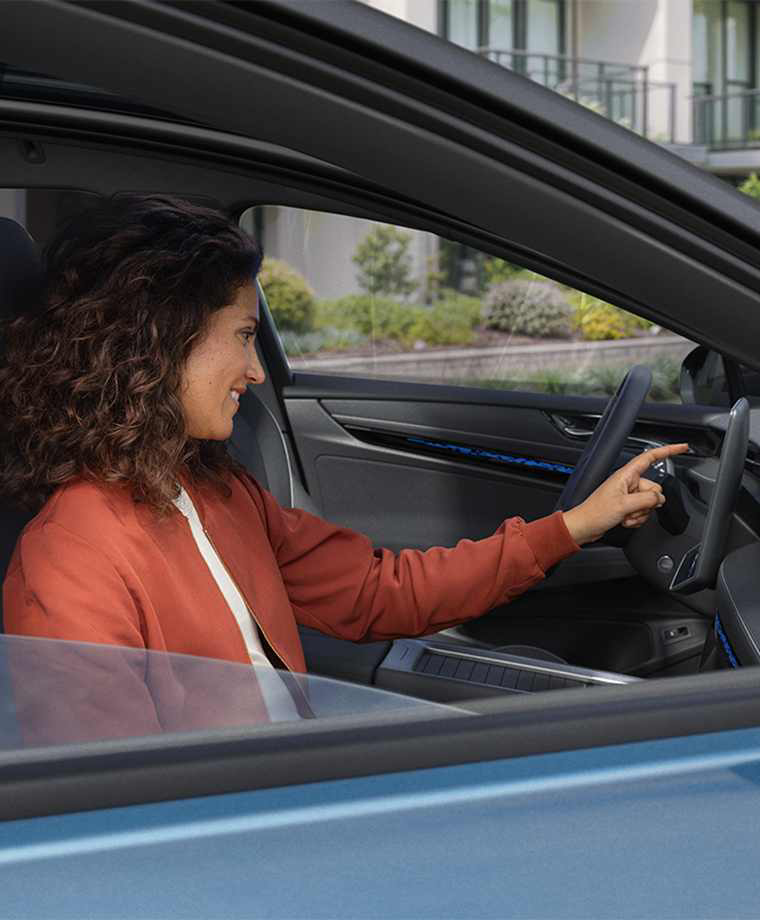 Una mujer sentada dentro de un Volkswagen usando la pantalla del salpicadero
