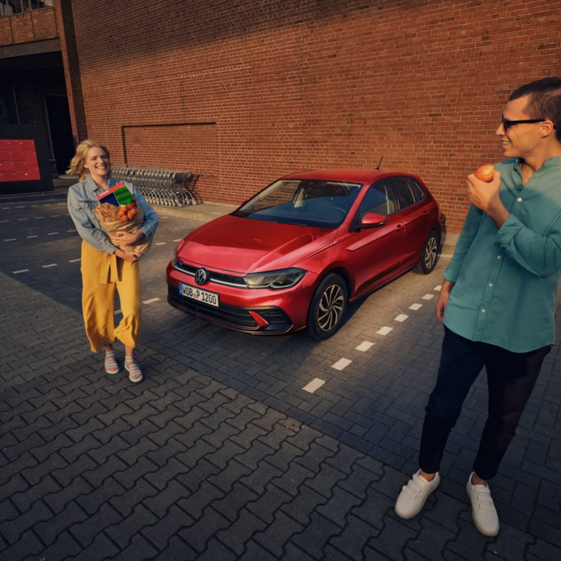 Una pareja frente a un Volkswagen rojo