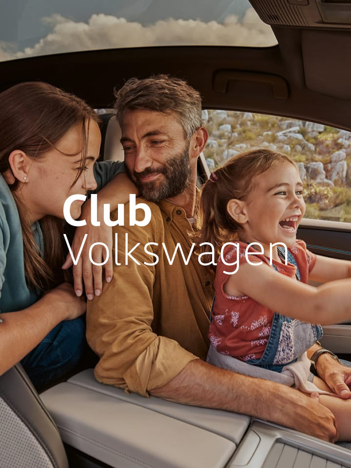 Dos niñeces con un adulto dentro de un Volkswagen con el logo del Club Volkswagen