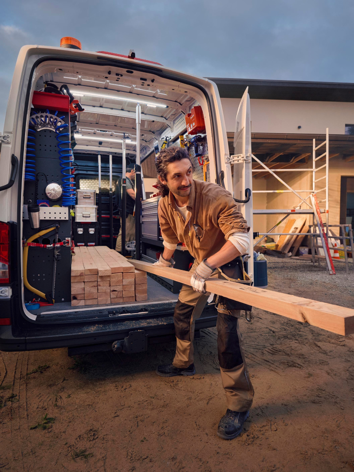 Un hombre sacando una tabla de madera de una furgoneta Volkswagen