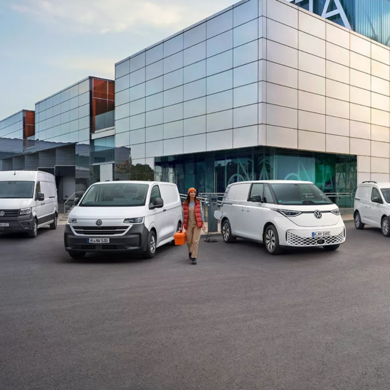 Una mujer entre varias furgonetas Volkswagen blancas