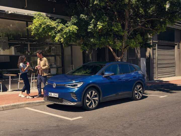 Dos personas junto a un Volkswagen ID.4 azul aparcado en la calle