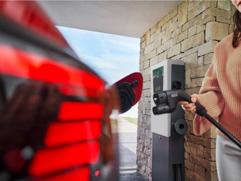 Una mujer conectando un cargador eléctrico a un Volkswagen