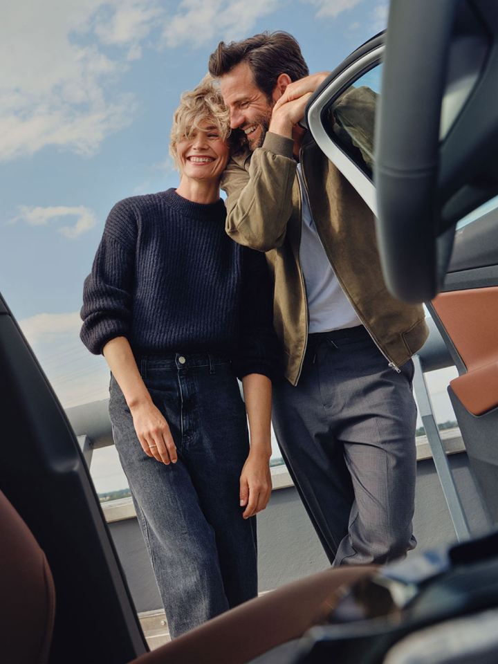 Una pareja sonriendo vistos desde el interior de un Volkswagen con la puerta abierta