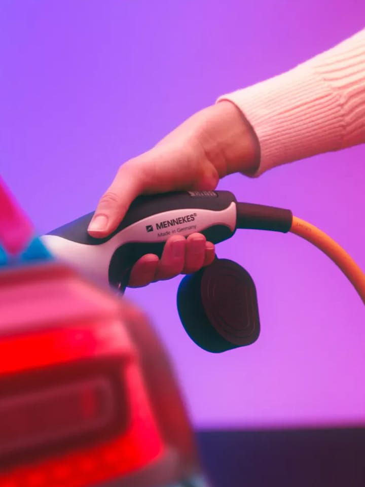 Detalle de una mano conectando un cargador a un Volkswagen