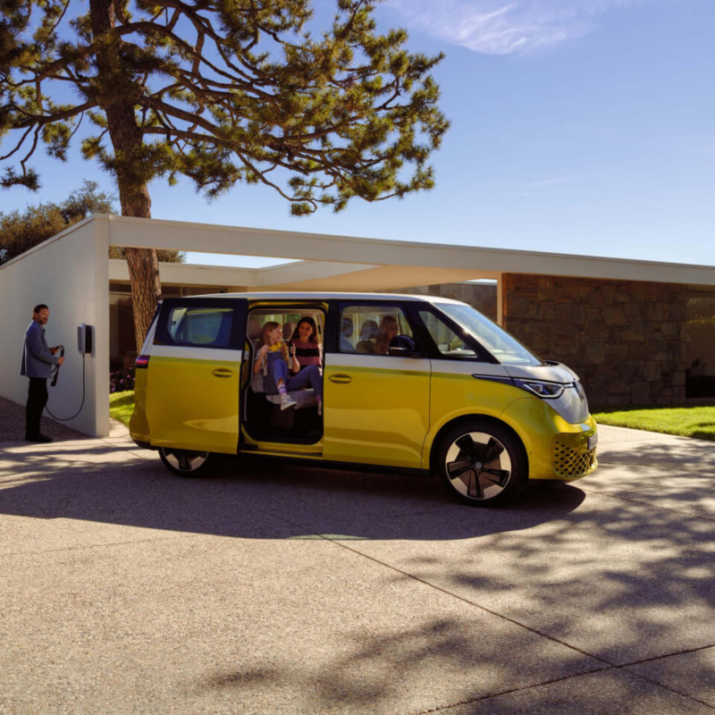 Una familia con una Volkswagen ID. Buzz amarilla aparcada en casa