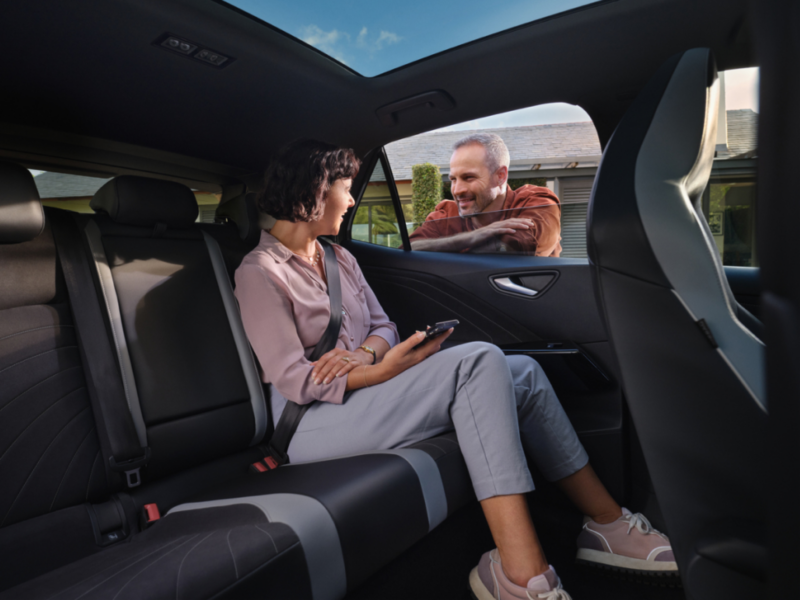 Un chica sentada en el interior de un Volkswagen hablando con un señor en el exterior