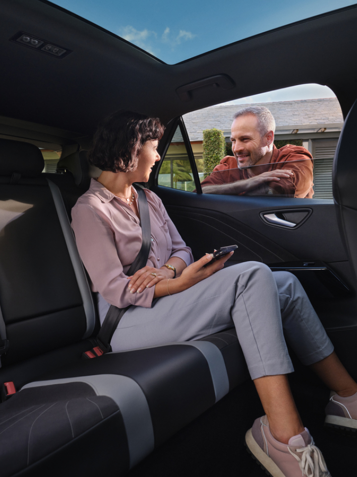 Una chica sentada en un Volkswagen hablando con un hombre a través de la ventanilla