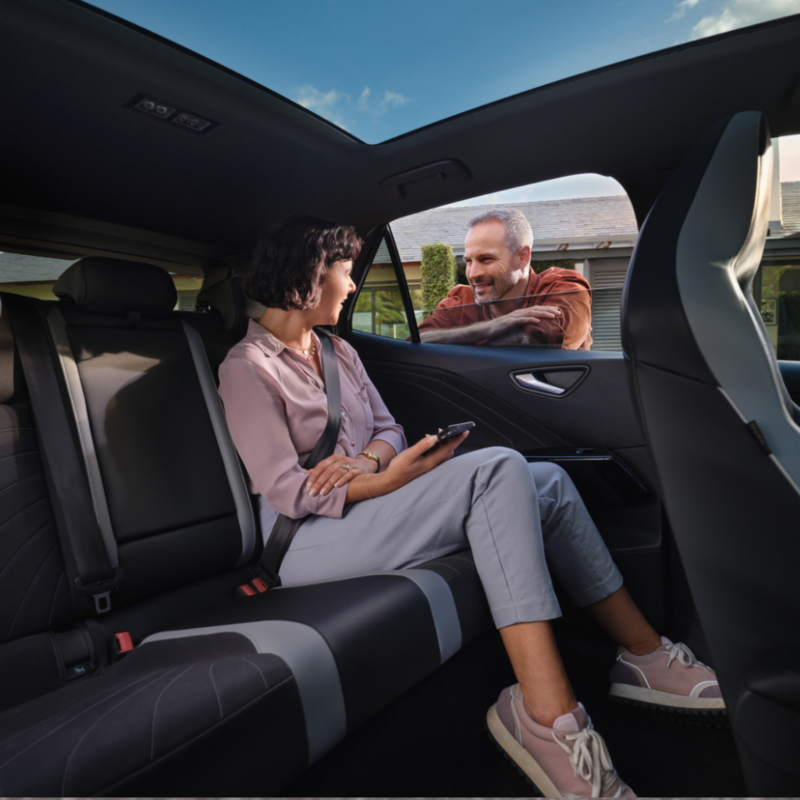 Chica sentada en el interior de un Volkswagen hablando con un chico en el exterior