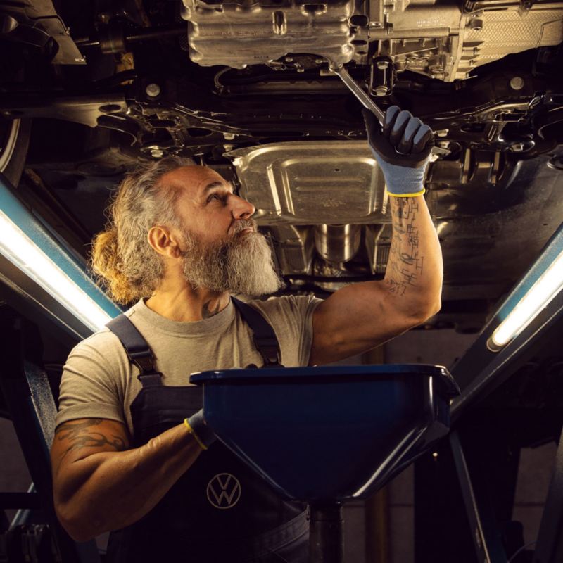 Un mecánico revisando la parte baja de un Volkswagen