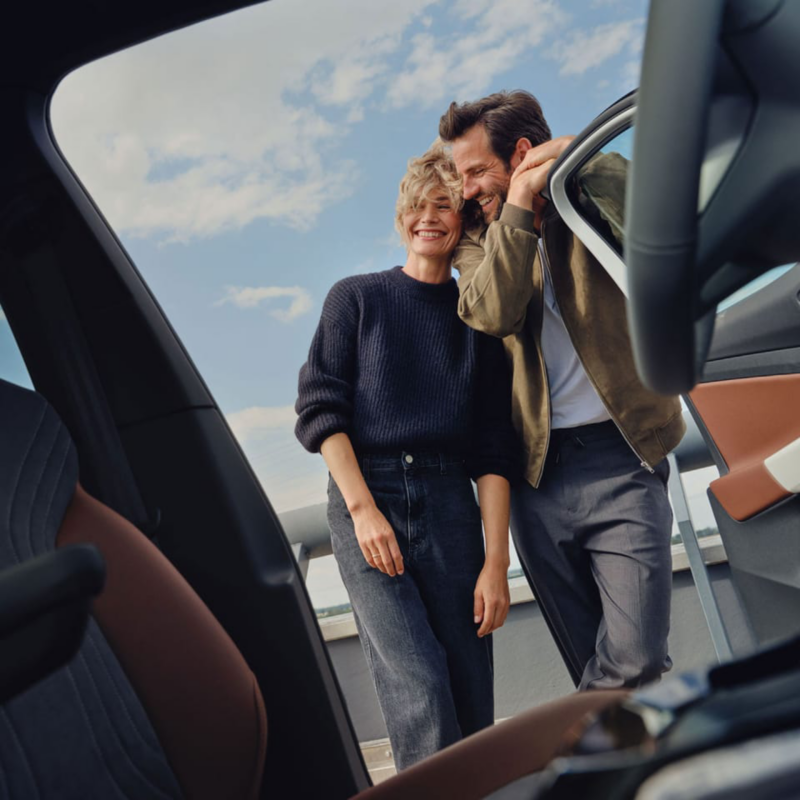 Una pareja fuera de un Volkswagen estacionado fuera de una casa