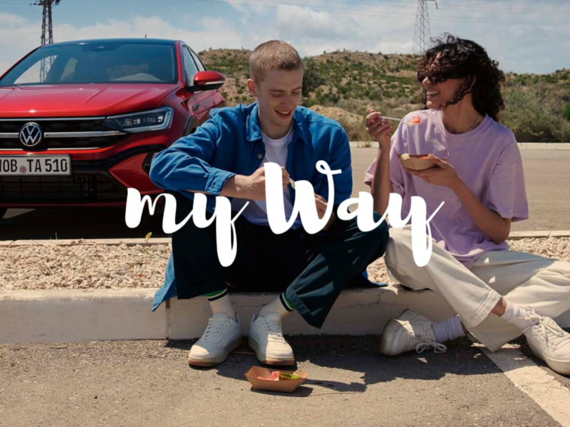 Dos chicos sentados delante de un Volkswagen con el logo my way