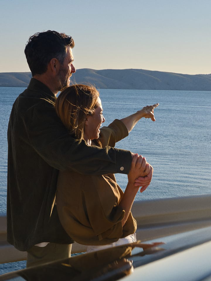 Una pareja frente al mar junto a un Volkswagen