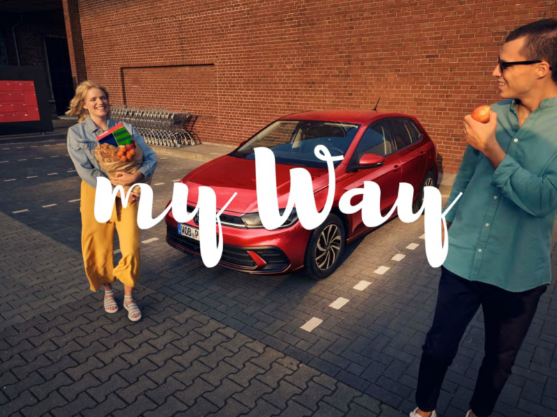 Una pareja junto a un Volkswagen rojo en el supermercado y el logo de My Way