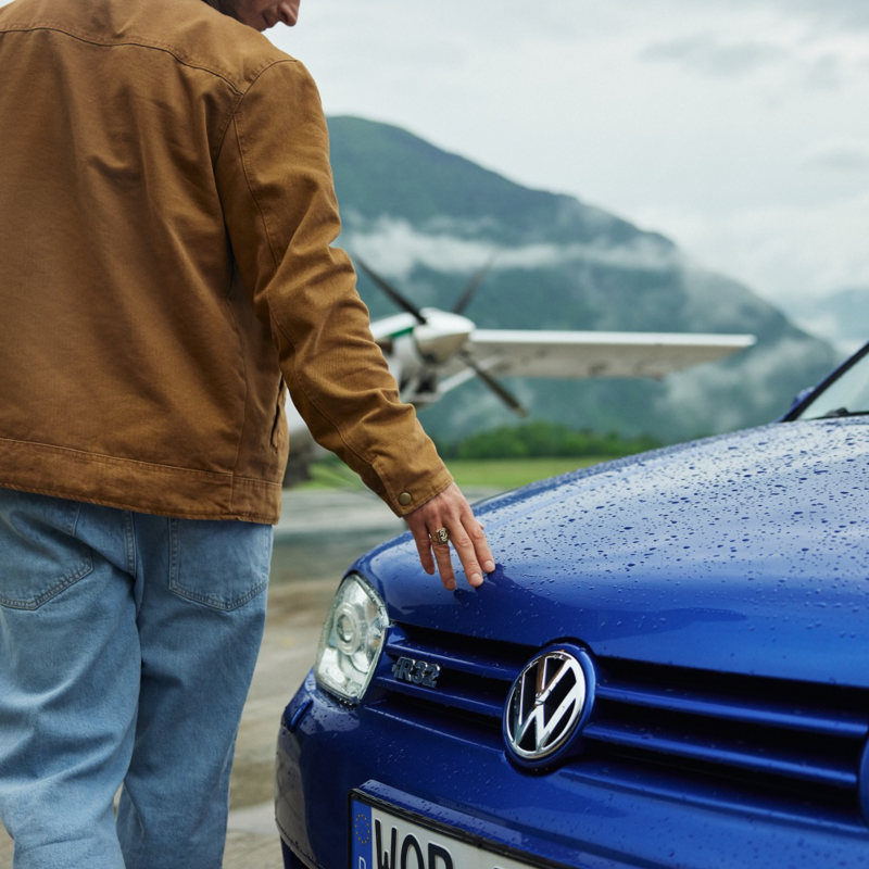 Un hombre tocando la parte delantera de un Golf GTI de color azul oscuro