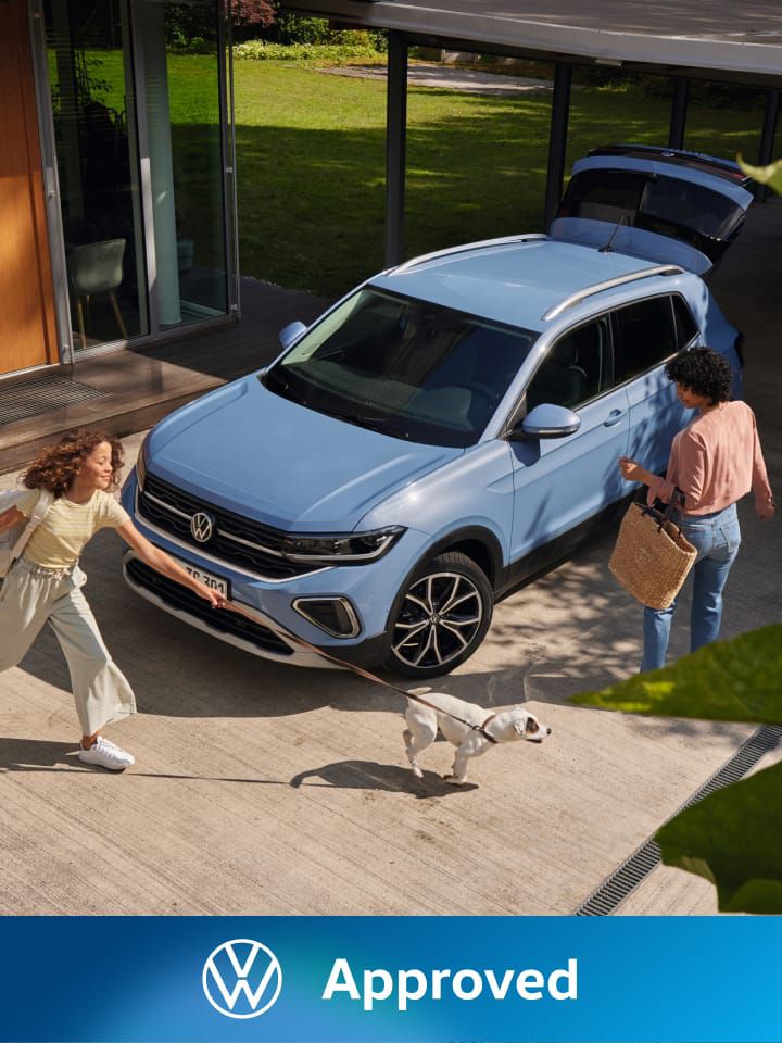 Dos mujeres al lado de un Volkswagen de color azul estacionado