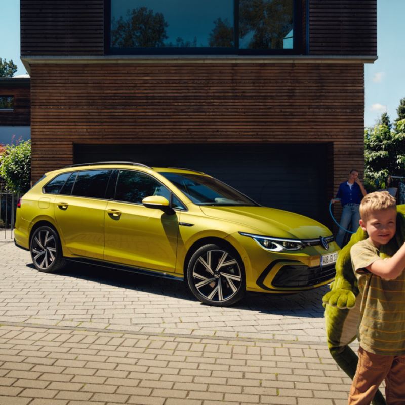 Golf Variant amarillo delante de un garage y un niño con un peluche