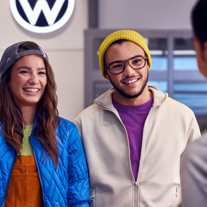 Una pareja sonriendo con un agente de servicio de Volkswagen