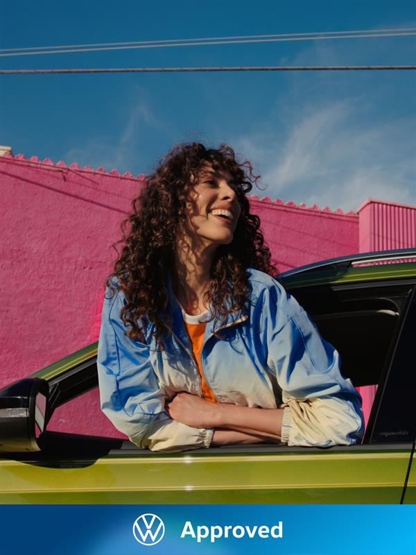 Una chica sonriendo asomada por la ventana de un Volkswagen de ocasión