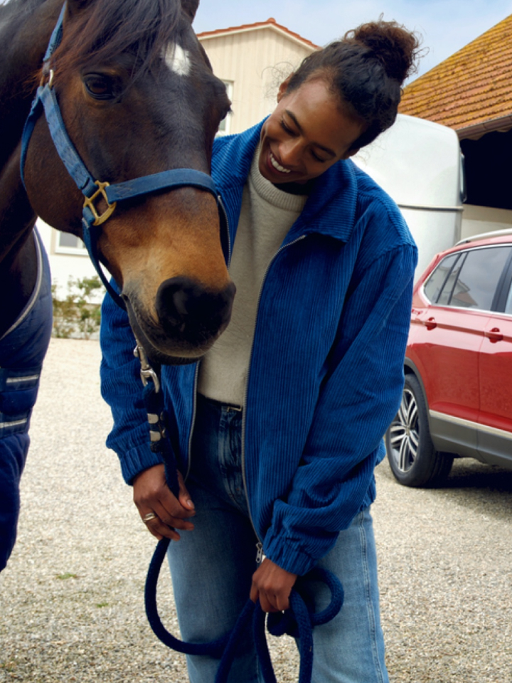 Un chico con un caballo y un Volkswagen SUV rojo al fondo