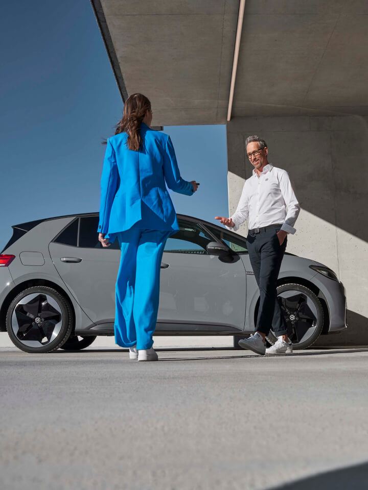 Una pareja al lado de un Volkswagen de color gris estacionado