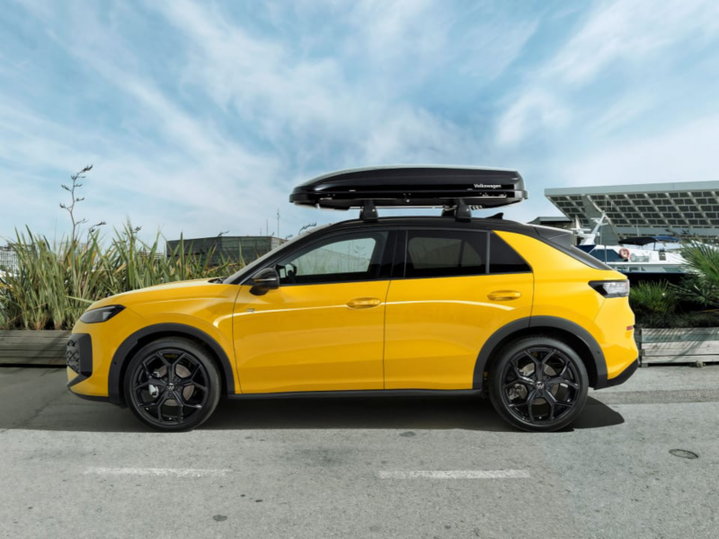 Un Volkswagen T-Roc amarillo parado con un panel solar detrás
