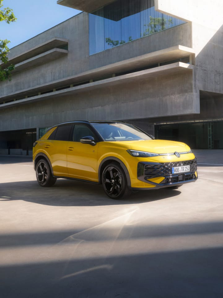 Volkswagen T-Roc amarillo parado frente un edificio de hormigón