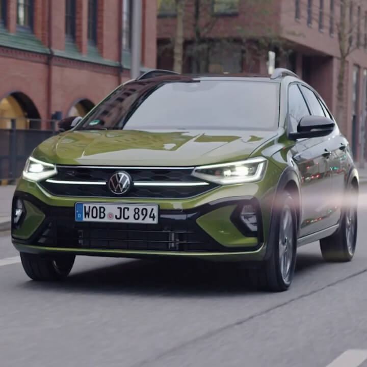 Un Volkswagen Taigo verde visto de frente circulando por la ciudad