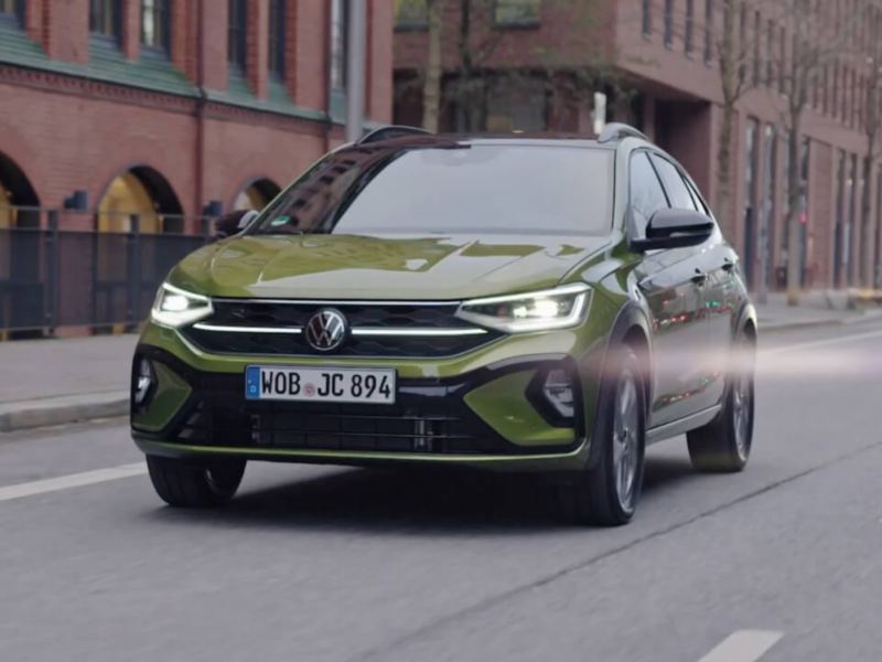 Un Volkswagen Taigo verde visto de frente circulando por la ciudad