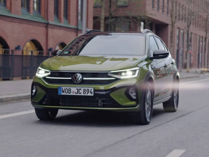 Un Volkswagen Taigo verde visto de frente circulando por la ciudad