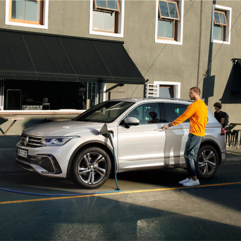 Un chico abriendo un Volkswagen Tiguan híbrido enchufable