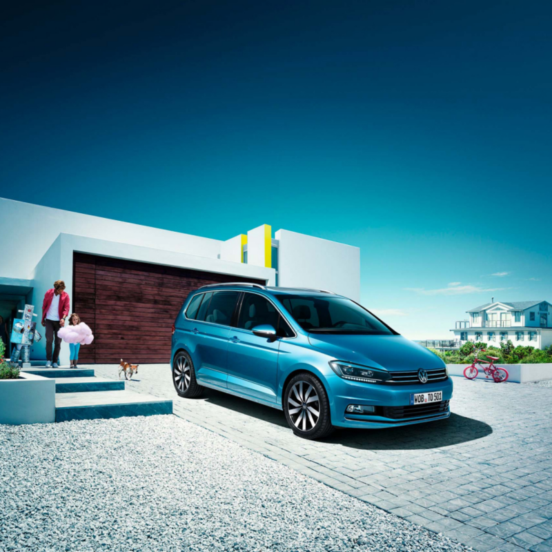 Un Volkswagen Touran de color azul estacionado fuera de una casa