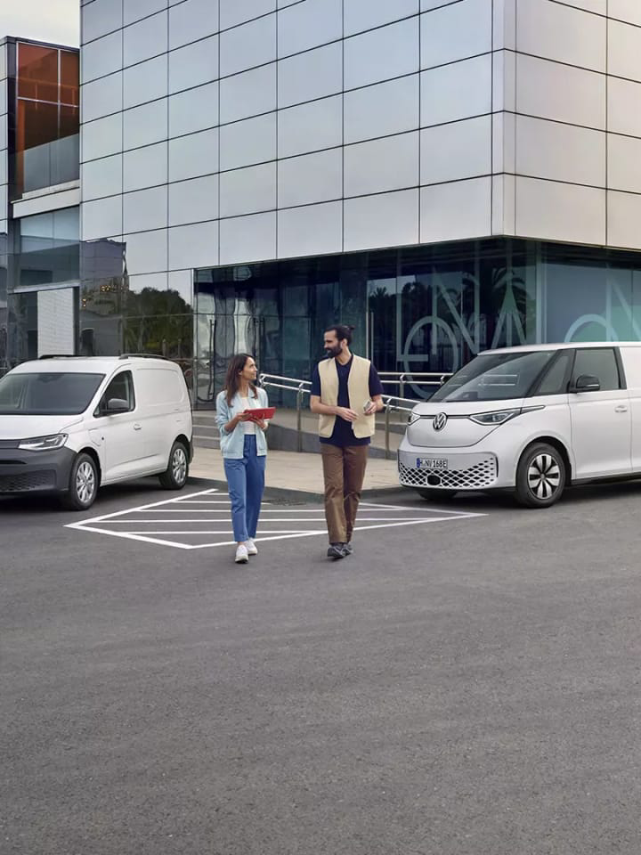 Dos personas junto a furgos Volkswagen frente a un concesionario