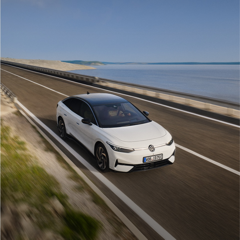Un Volkswagen de color blanco con el techo negro circulando por una carretera