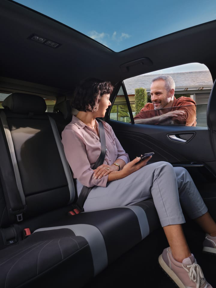 Una mujer dentro de un Volkswagen y en la ventana un hombre apoyado