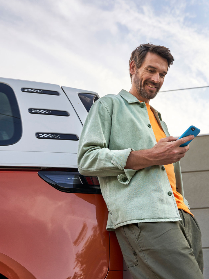 Un hombre con un móvil en la mano apoyado en un Volkswagen