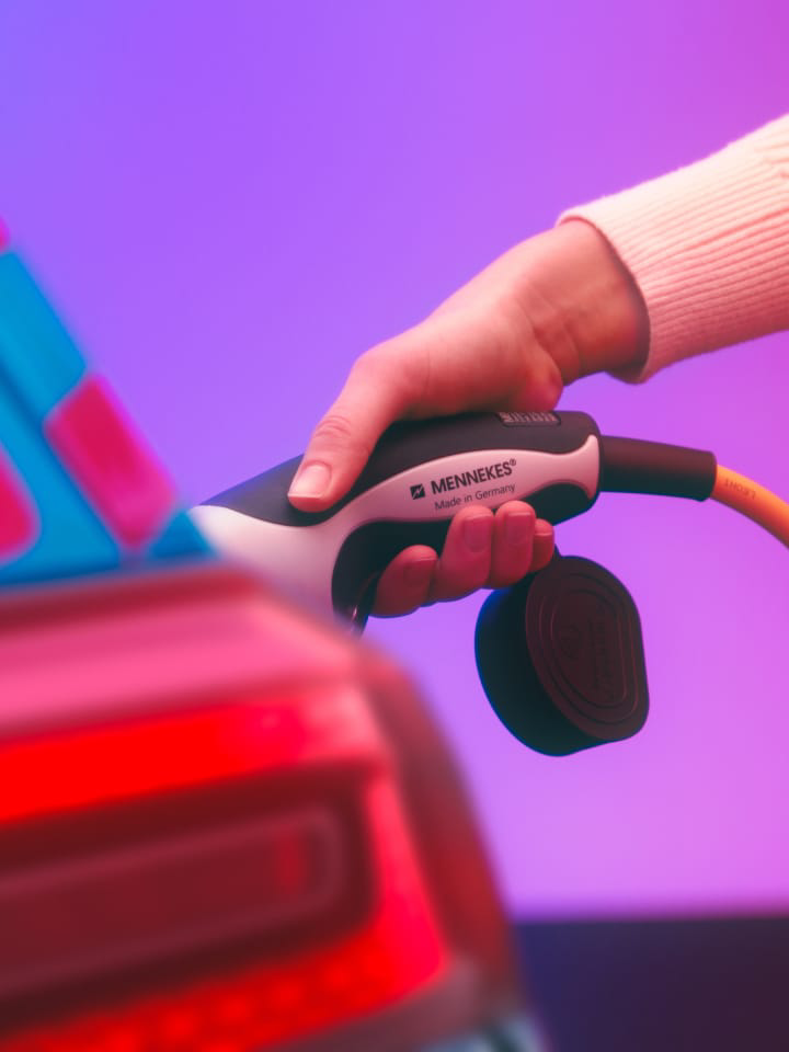 Detalle de una mano conectando un cargador eléctrico a un Volkswagen ID.