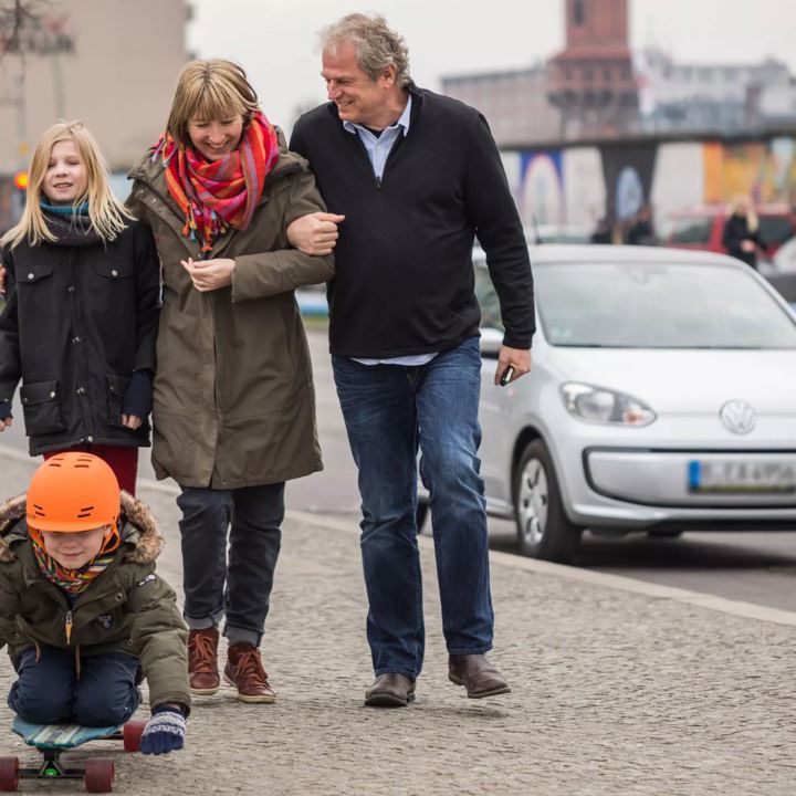 Familia paseando por la ciudad de Berlin con un Volkswagen e-up! blanco de fondo