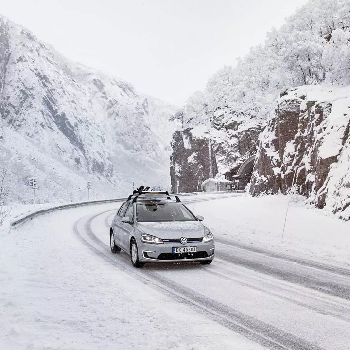 Volkswagen e-Golf Gris con porta esquís circulando por una carretera nevada
