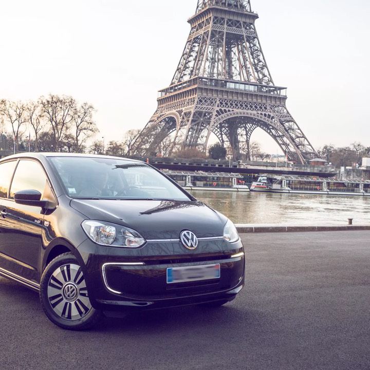 Un Volkswagen e-Up! negro aparcado frente al río Sena y la torre Eiffel