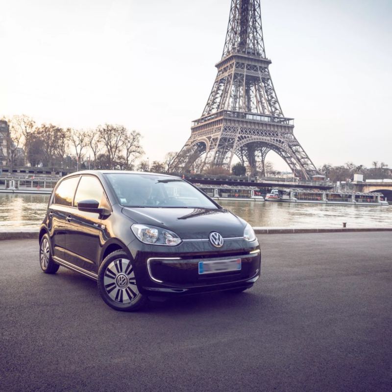 Un Volkswagen e-Up! negro aparcado frente al río Sena y la torre Eiffel