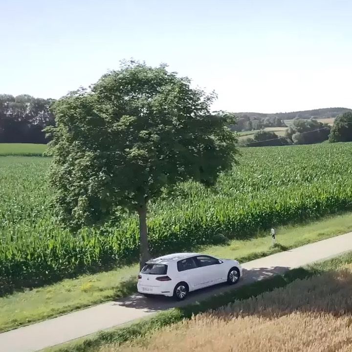 Volkswagen e-up! blanco circulando por el campo por el día pasando junto a un arbol